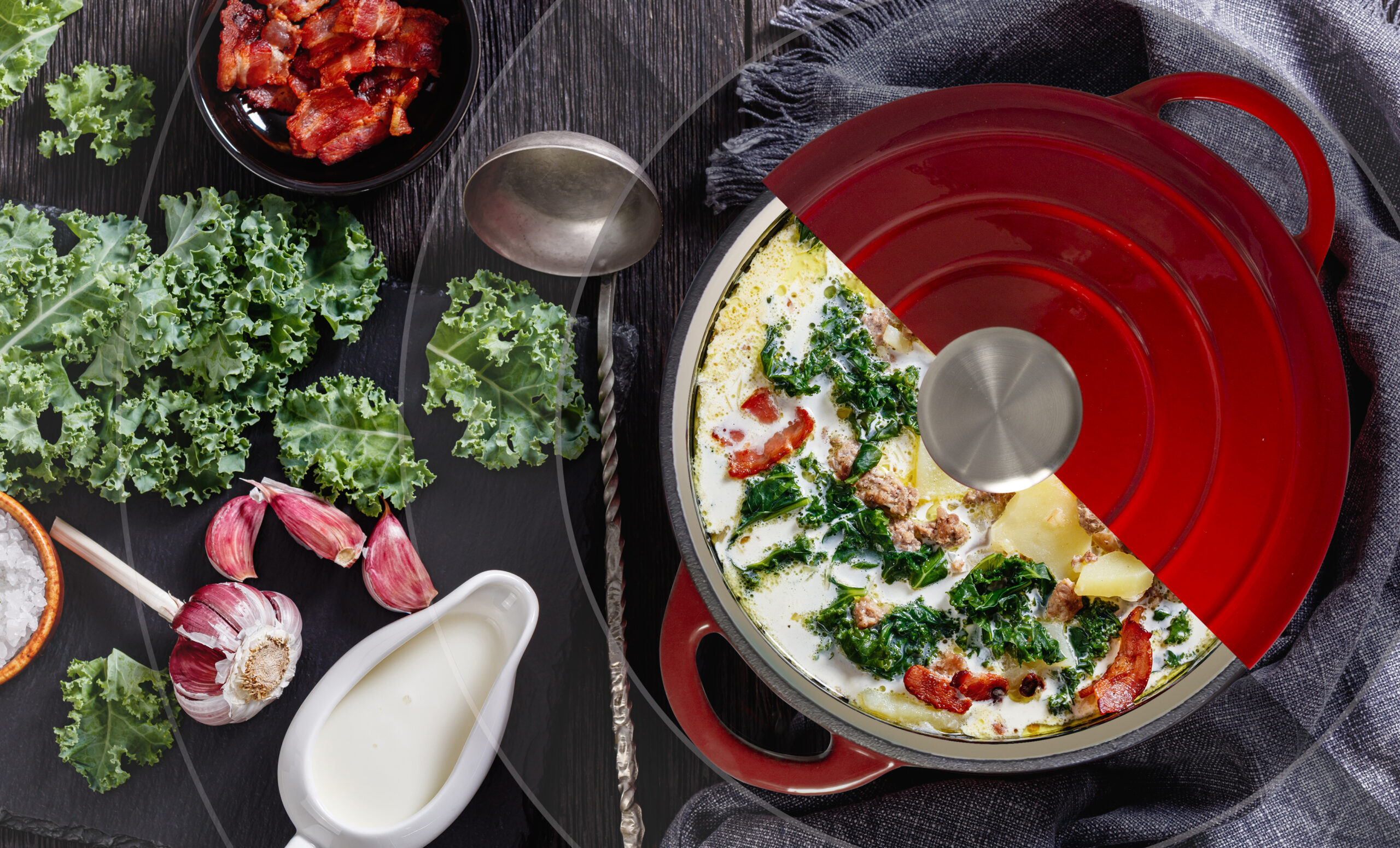 Zuppa Toscana, hearty Tuscan Soup loaded with Italian sausage, kale, bacon and potatoes in red pot with ingredients  and soup ladle on dark wooden table, horizontal view from above, flat lay