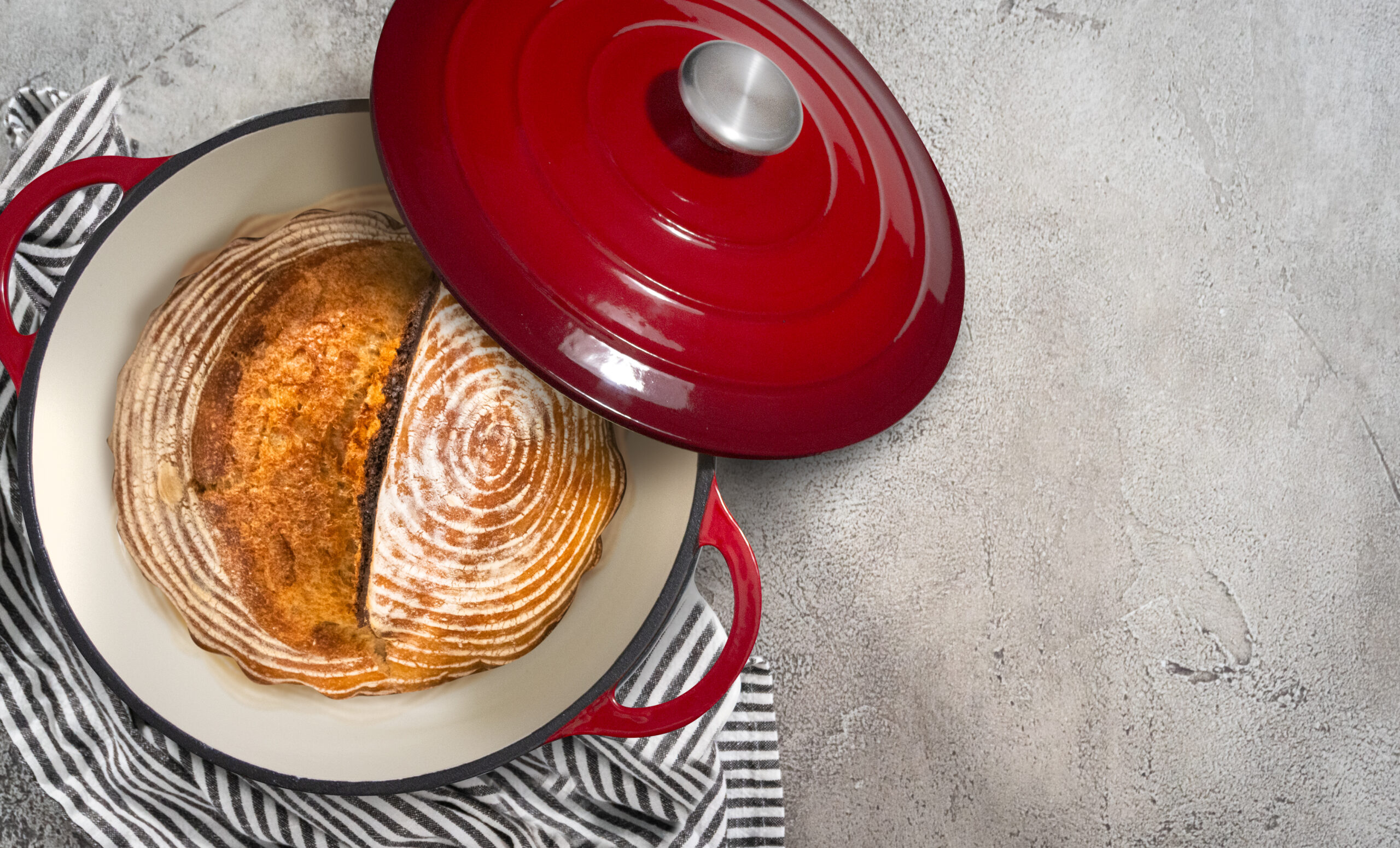 Flat lay. Freshly baked loaf of a wheat sourdough bread with marks from bread proofing basket in enameled cast iron dutch oven.